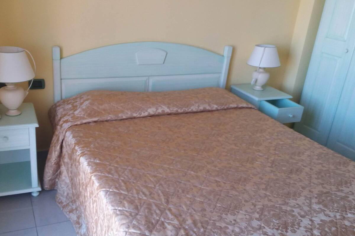 Un dormitorio con cama, mesitas de noche y lámparas.