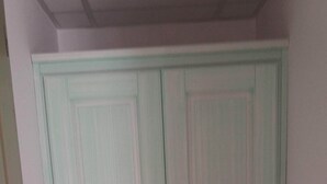 Una habitación con un armario grande, piso de baldosas y una pared lisa.