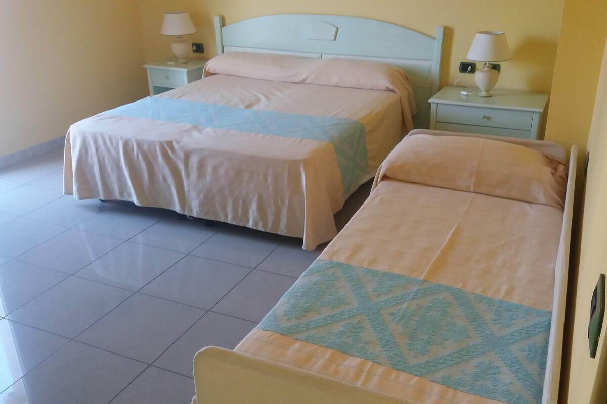 Habitación de hotel con dos camas individuales, cada una con mesita de noche y lámpara.