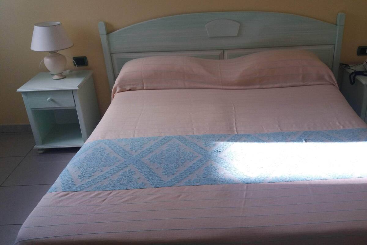 Una cama con una colcha estampada, dos mesitas de noche con lámparas y un tocador con un teléfono.