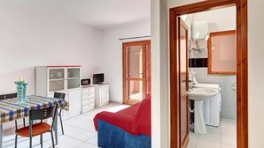 A compact room with a bed, a dining table with chairs, a small kitchenette, and a bathroom. - Apartment in San Teodoro (San Teodoro (SS))