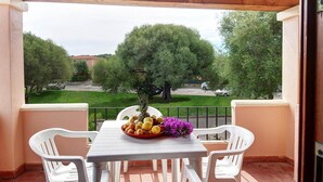 A balcony with a table set for two, a bowl of fruit, and a vase of flowers. - Apartment in San Teodoro (San Teodoro (SS))