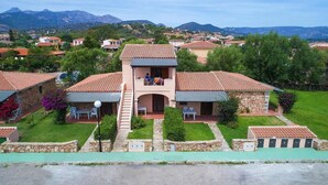 A two-story building with a central balcony, surrounded by a well-maintained lawn and stone walls. - Apartment in San Teodoro (San Teodoro (SS))