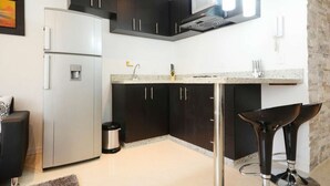 A modern kitchen with dark cabinets, a white refrigerator, a granite countertop, and a bar stool. - Two Bedroom Middle of Park lleras AC, Hot tub Bars downstairs (Medellin)