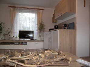 A kitchen with a TV, cabinets, and a table with branches and glasses. - Bungalow Vincent, with terrace, barbecue & WLAN - Bungalow with garden, terrace and (Zempin)