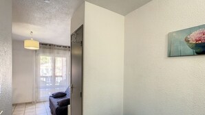 Una habitación con una cama azul, una puerta que da a un balcón y un cuadro en la pared.