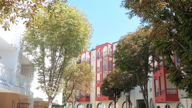 Un patio con un sendero, bancos y un edificio de arquitectura roja y blanca.