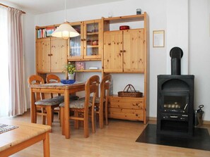 Ein gemütliches Wohnzimmer mit einem Holzespeisetisch, Stühlen, einem Kamin und einer Vitrine.