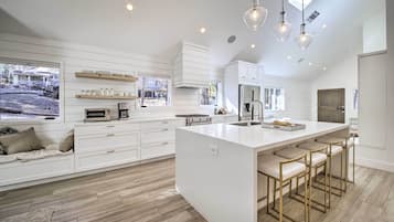 Una cocina moderna con armarios blancos, una isla grande con taburetes de bar e iluminación colgante.