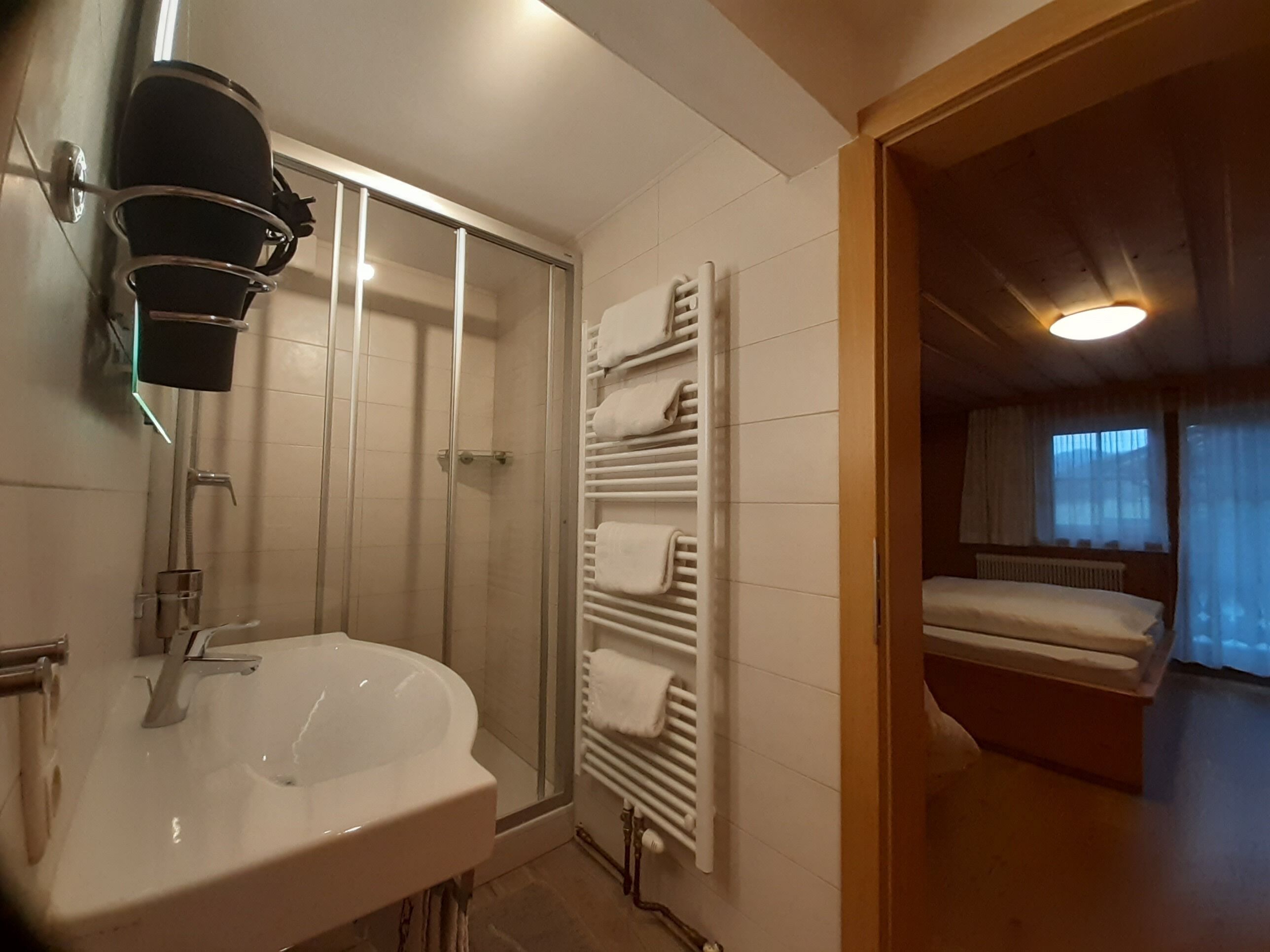 A bathroom with a sink, shower, and towel rack.