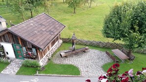 A rustic building with a stone pathway leading to a wooden bench and a small fountain. - Unterlettlhof (Saalfelden am Steinernen Meer)