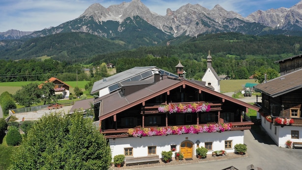 A traditional chalet with a wooden balcony, surrounded by lush greenery and mountains in the background. - Unterlettlhof (Saalfelden am Steinernen Meer)