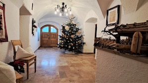 A narrow hallway with a wooden door at the end, a decorated Christmas tree, and a rustic wooden shelf with various items. - Unterlettlhof (Saalfelden am Steinernen Meer)