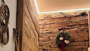 A wooden staircase with a rustic wall, a small potted plant, and a wreath on the wall. - Unterlettlhof (Saalfelden am Steinernen Meer)