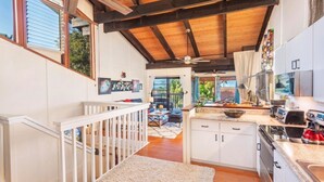 A spacious kitchen with a wooden ceiling, white cabinets, and a large island. - North Shore Kauai- AC, pool, lanai; near beaches, golf, walking path to shops (Princeville)