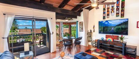 A spacious living room with a large TV, comfortable seating, and a view of the outdoors.