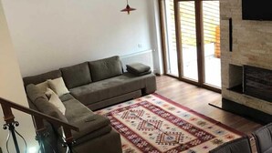A modern living room with a sofa, a fireplace, and a staircase. - Meshtekna (Brezovicë)
