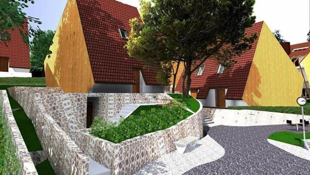 A residential area with houses featuring red-tiled roofs and a central landscaped area with a stone wall and greenery. - Meshtekna (Brezovicë)