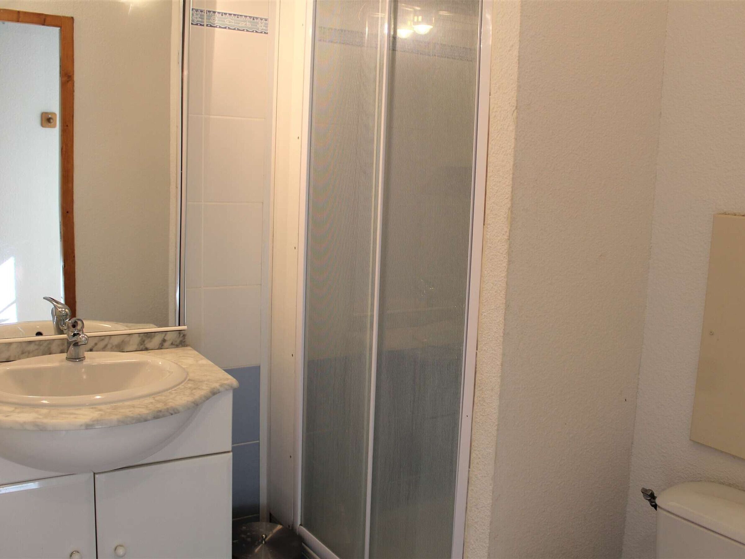 A bathroom with a marble sink, a toilet, and a glass-enclosed shower.