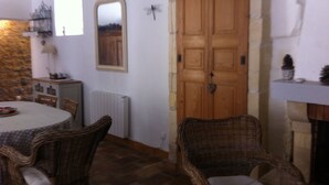 A dining area with wicker chairs, a round table, and a stone wall. - Character house at the foot of the castle. Shaded terrace (Boulbon)