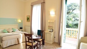 Une chambre d’hôtel avec un lit, une petite table avec des chaises, une armoire et une vue sur l’extérieur.