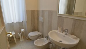 Un baño con inodoro, bidé, lavabo y espejo.