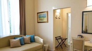 A living room with a sofa, a chair, a small table, a painting, and a mirror. - B&B Dimora Salviati -  Suite (Firenze)