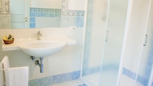 A bathroom with a white sink, a glass shower enclosure, and blue-tiled walls. - B&B Dimora Salviati -  Suite (Firenze)