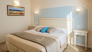 A bedroom with a bed, bedside tables, a nightstand, a wall-mounted lamp, and a painting. - B&B Dimora Salviati -  Suite (Firenze)