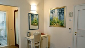 A room with a wooden herringbone floor, a white door, a small table with a chair, a wall-mounted light, and two framed paintings. - B&B Dimora Salviati -  Suite (Firenze)