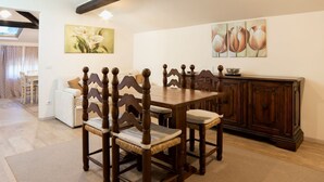A dining area with a wooden table and chairs, a white sofa, and a cabinet. - Apartment with terrace ovelooking Florence (Firenze)