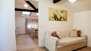 A living room with a sofa, a painting of flowers, and a wooden floor. - Apartment with terrace ovelooking Florence (Firenze)