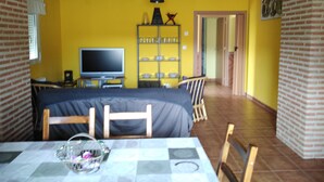 Een kamer met een bed, een televisie, een plank met servies en een deur naar een andere kamer.