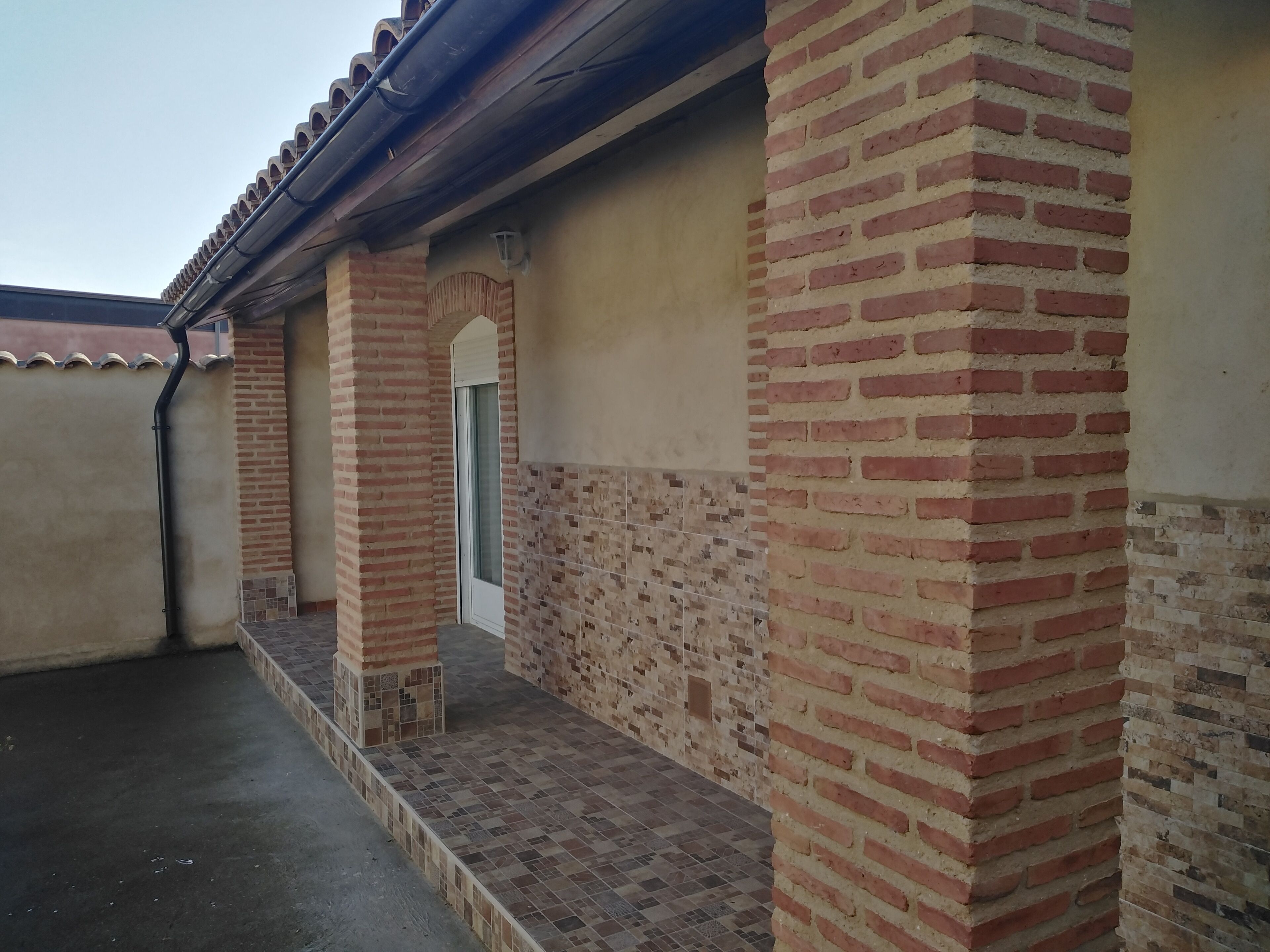 A covered outdoor area with brick columns and a tiled floor.