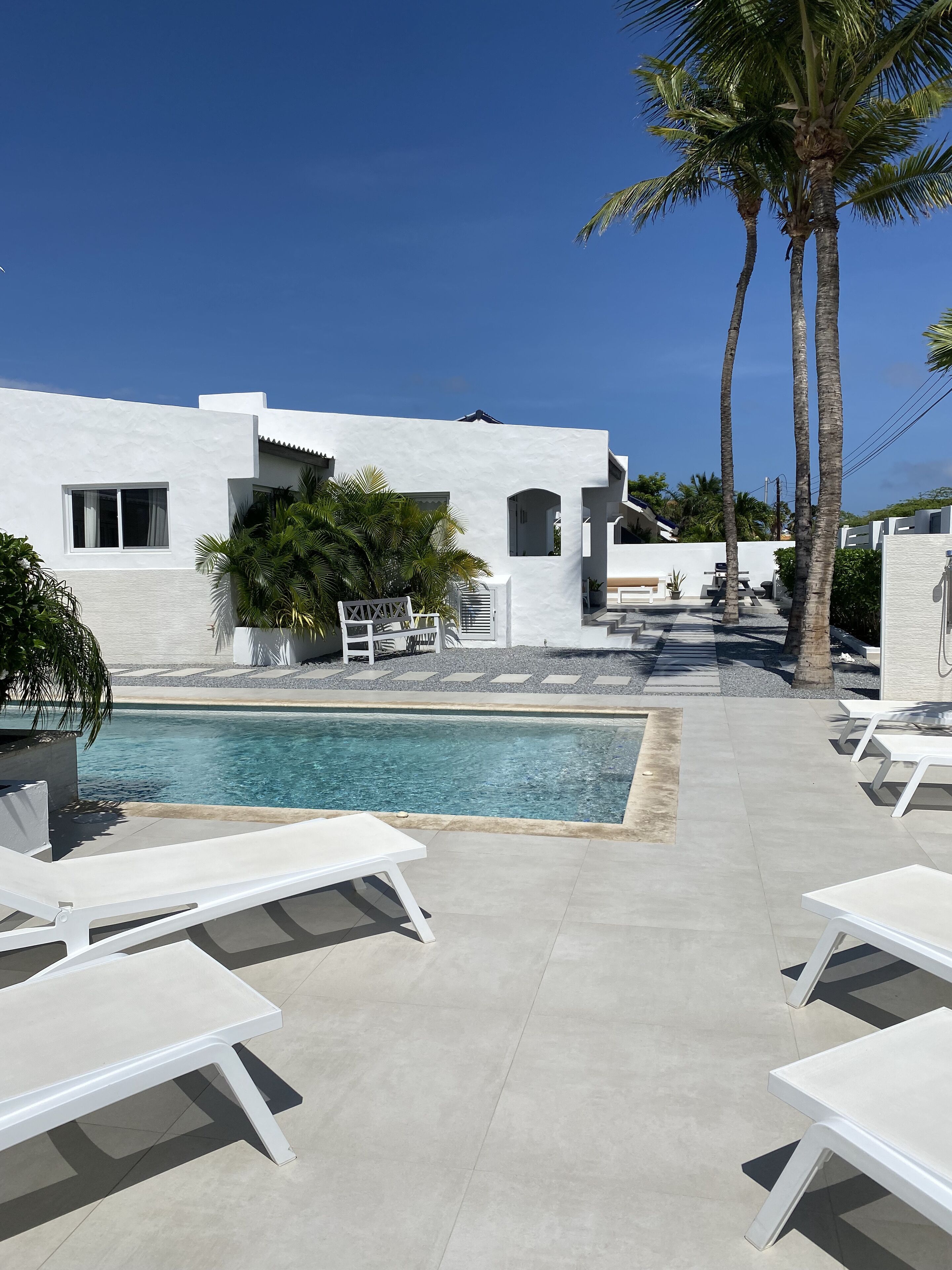 Un espace piscine moderne avec des chaises longues blanches et une piscine à l’eau d’un bleu cristallin.