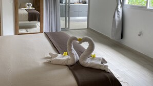 Habitación de hotel con cama, balcón y vista a la vegetación.