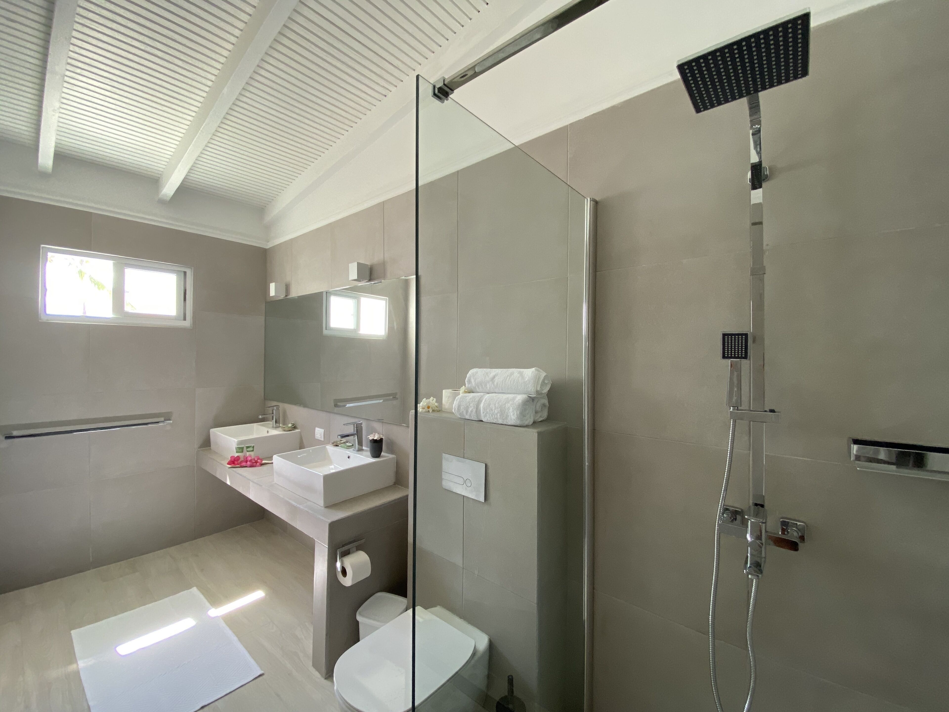 Un baño moderno con ducha de vidrio, lavamanos e inodoro.