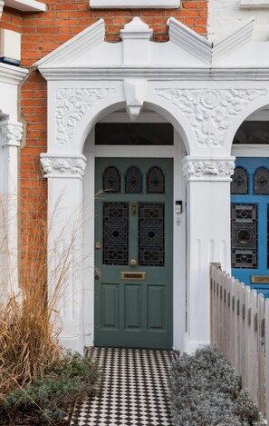 A traditional house with a green door, white arches, and a checkered pathway leading to the entrance. - Stylish Double en suite bedroom in Crouch End (London)