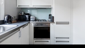 A modern kitchen with white cabinets, stainless steel appliances, a gas stove, a toaster, and a kettle. - Stylish Double en suite bedroom in Crouch End (London)