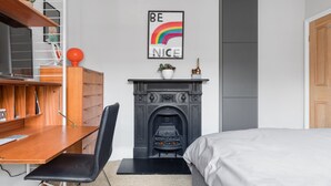 A bedroom with a wooden desk, a black chair, a fireplace, a bed, and a motivational poster on the wall. - Stylish Double en suite bedroom in Crouch End (London)