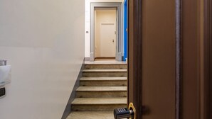 Eine Treppe f ührt zu einem Raum mit einer Tür, einer Fernbedienung auf dem Boden und einem an der Wand befestigten Gerät.