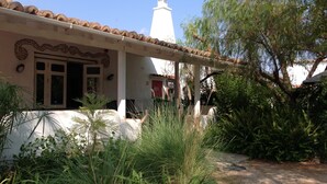 A traditional building with a tiled roof, a white tower, and a covered porch with plants. - Fazendinha (Tavira)