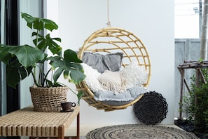 Relax in a serene space with a hanging chair, woven basket, and potted plant.