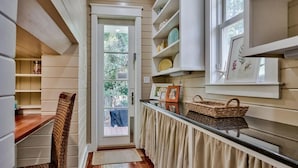 A narrow hallway with wooden walls, a door leading outside, and shelves with decorative items. - Luxury Old Seagrove, BeachComer, Walk to Beach and Seaside, 3 King BRs, Private Heated Pool (Seagrove Beach)