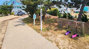 A residential street with a sidewalk, parked cars, and a sign indicating 'Ocean Dunes'. - BO DUCK - 3 BR Oceanside Home in the Heart of Duck - Perfect For A Small Family (Duck)