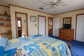 A bedroom with a bed, dresser, and a ceiling fan. There are doors leading to other rooms and a staircase. - BO DUCK - 3 BR Oceanside Home in the Heart of Duck - Perfect For A Small Family (Duck)