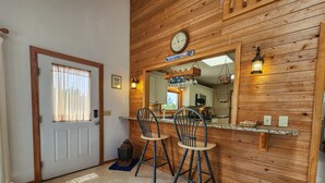 Una cocina con paneles de madera, un reloj y dos taburetes de bar.