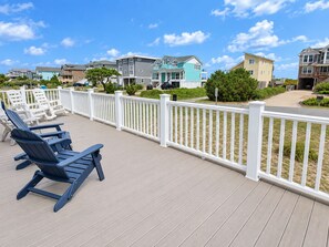 A deck with lounge chairs, a white fence, and houses in the background.