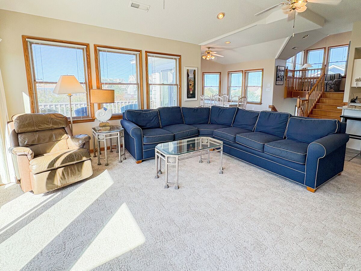 A living room with a sectional sofa, a glass coffee table, and a recliner.