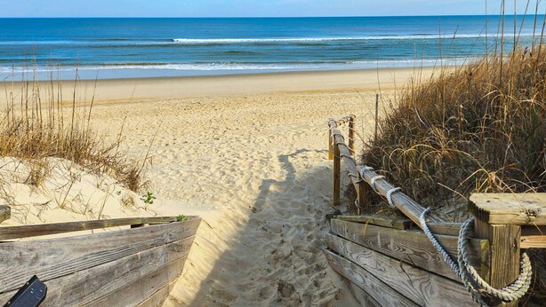 A wooden pathway leading to a sandy beach with a wooden fence and rope barrier. - Luzon - 5 BR, 4.5 BA, Oceanside home in Duck w/Private Pool (Duck)